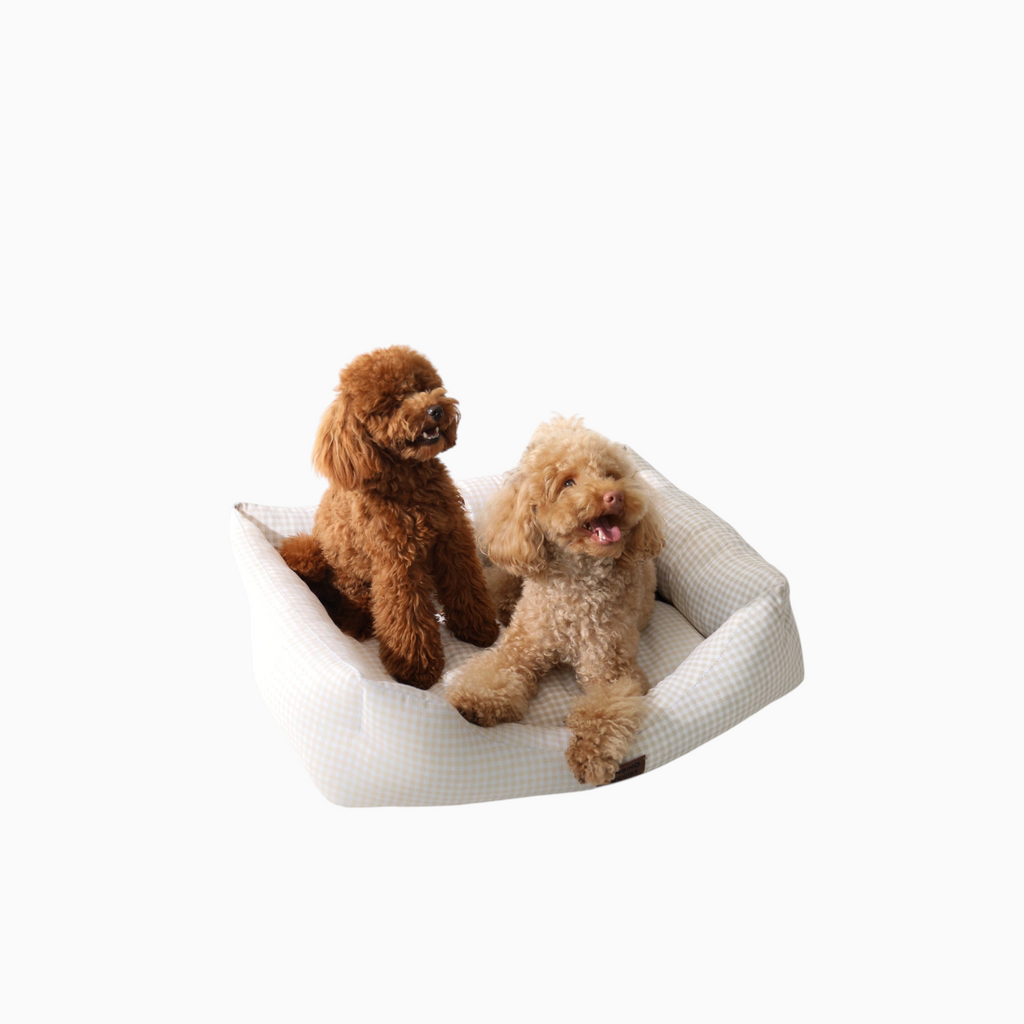 Dos perros caniche sobre una cama Bambino Doggies de estampado vichy beige con base antideslizante y relleno suave